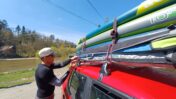 muž váže na střechu auta tři nafukovací paddleboardy